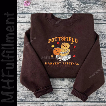Brown sweatshirt with 'Pottsfield Harvest Festival' design on a wooden surface