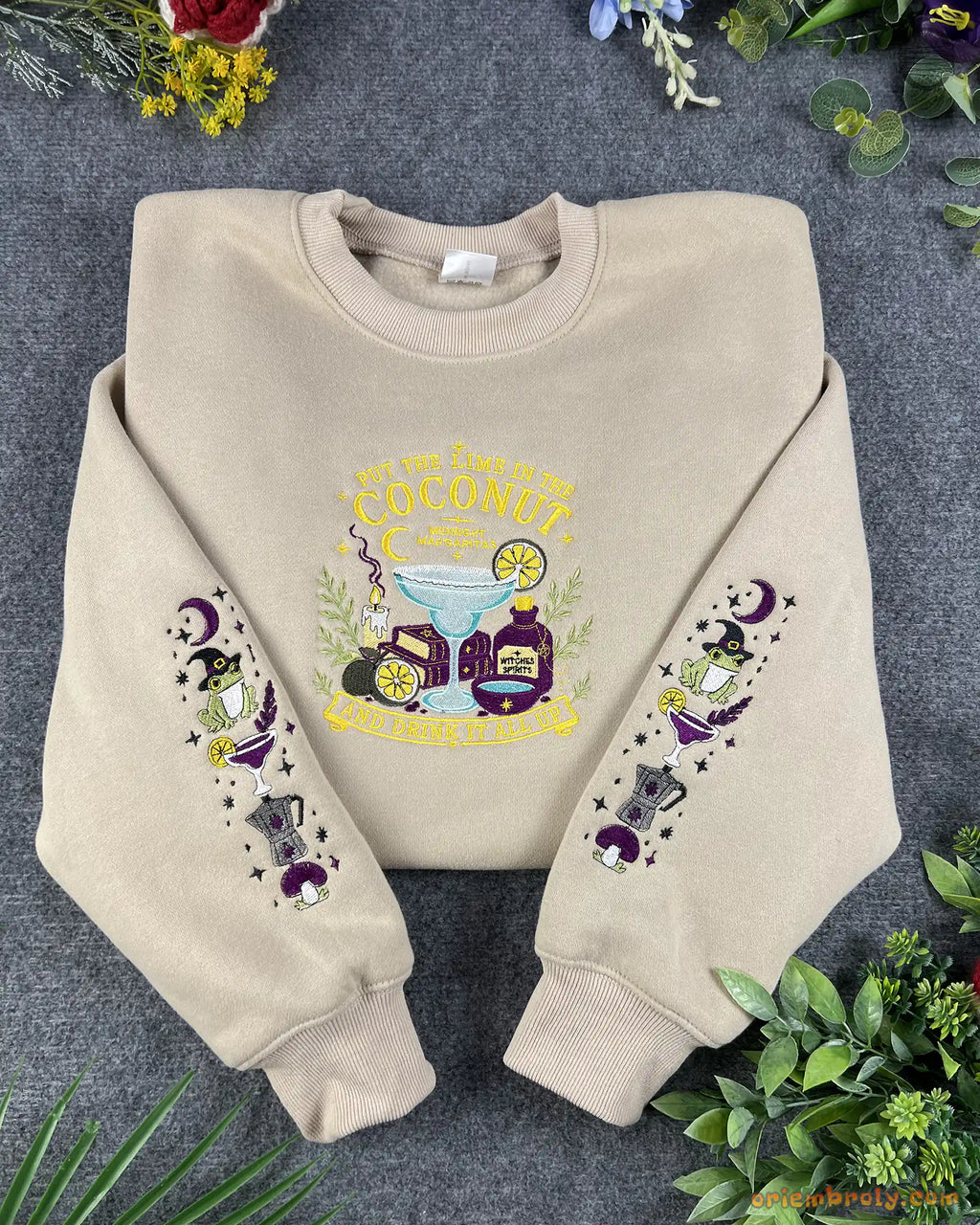 Flat lay of a beige Practical Magic embroidered sweatshirt with witchy frog and margarita sleeve details