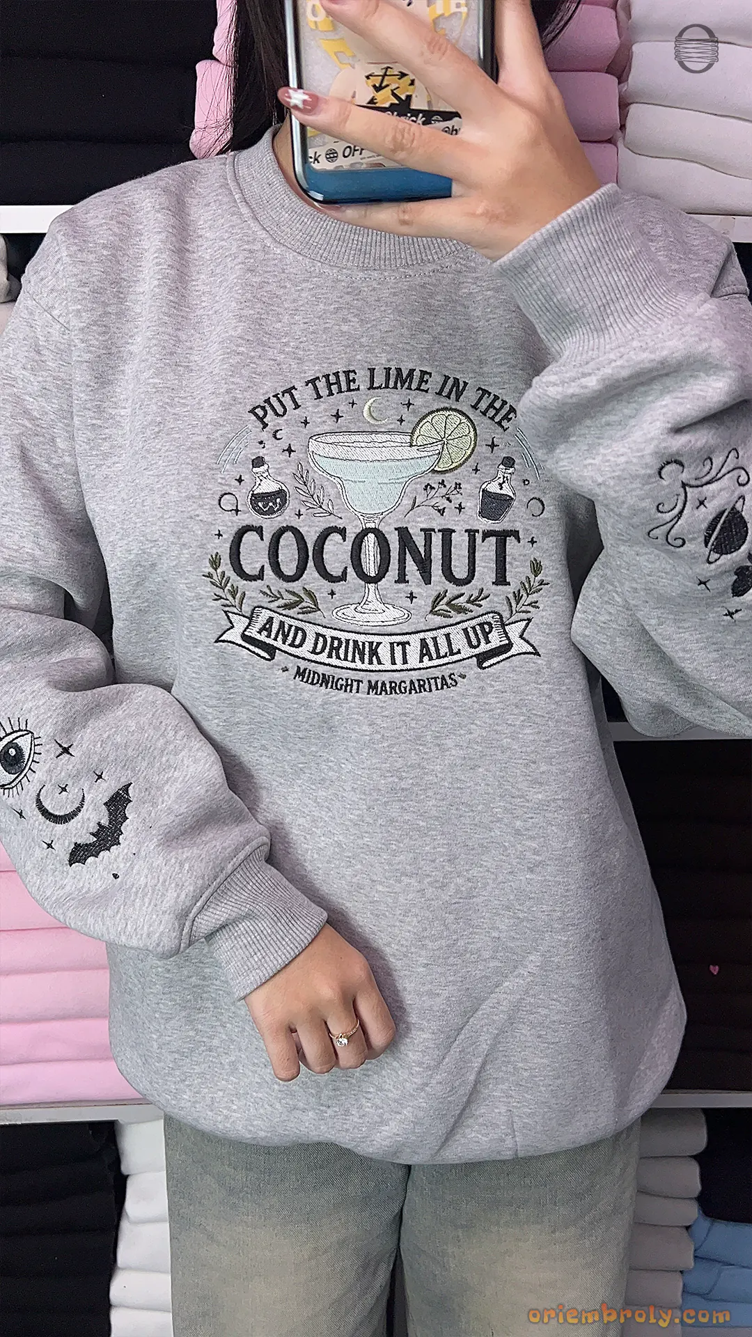 Model wearing a grey Practical Magic embroidered crewneck sweatshirt with celestial sleeve graphics