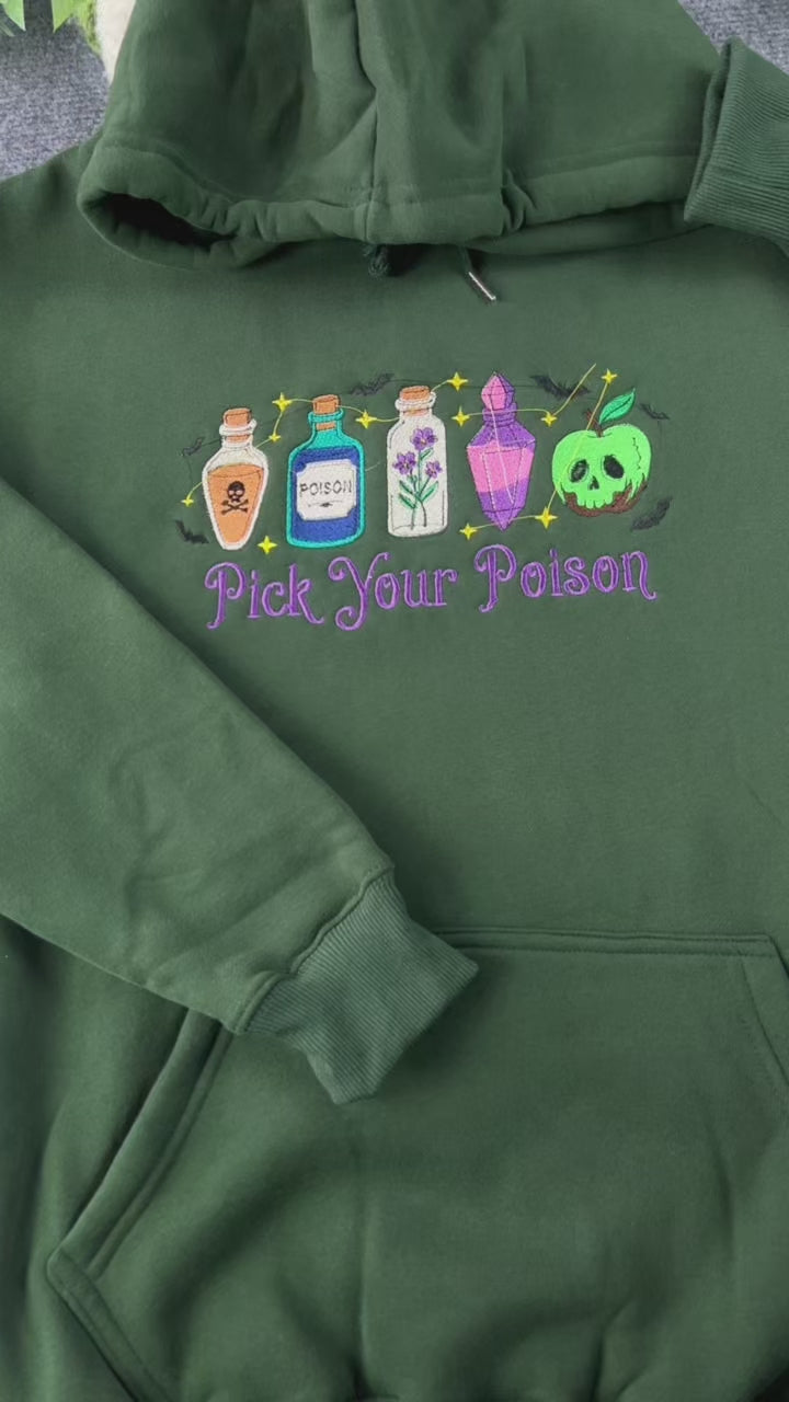 Video showing embroidered details of Pick Your Poison witchy potion bottles design on a green hoodie