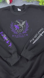 Video showing embroidered details of Basgiath War College dragons logo, dagger, and flying dragons sleeves on a black sweater