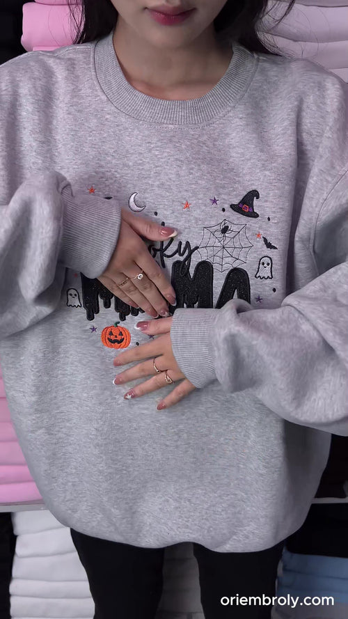 Close-up video of hands using small embroidery scissors to cut loose threads on a custom embroidered sweatshirt.
