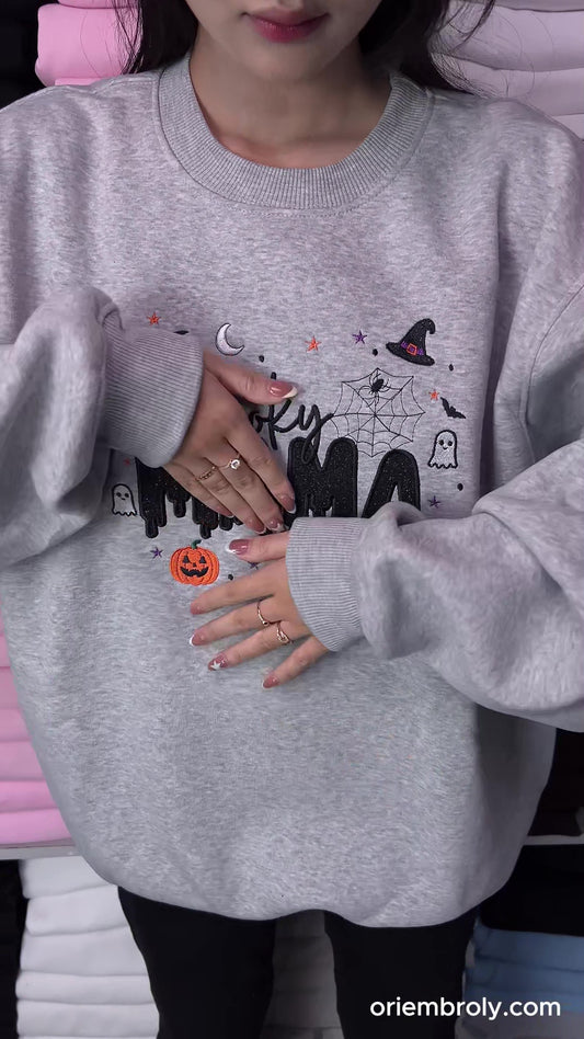 Close-up video of hands using small embroidery scissors to cut loose threads on a custom embroidered sweatshirt.