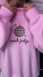 Video showing sparkling embroidered details of Couch Judge quote and disco ball on a light pink sweatshirt