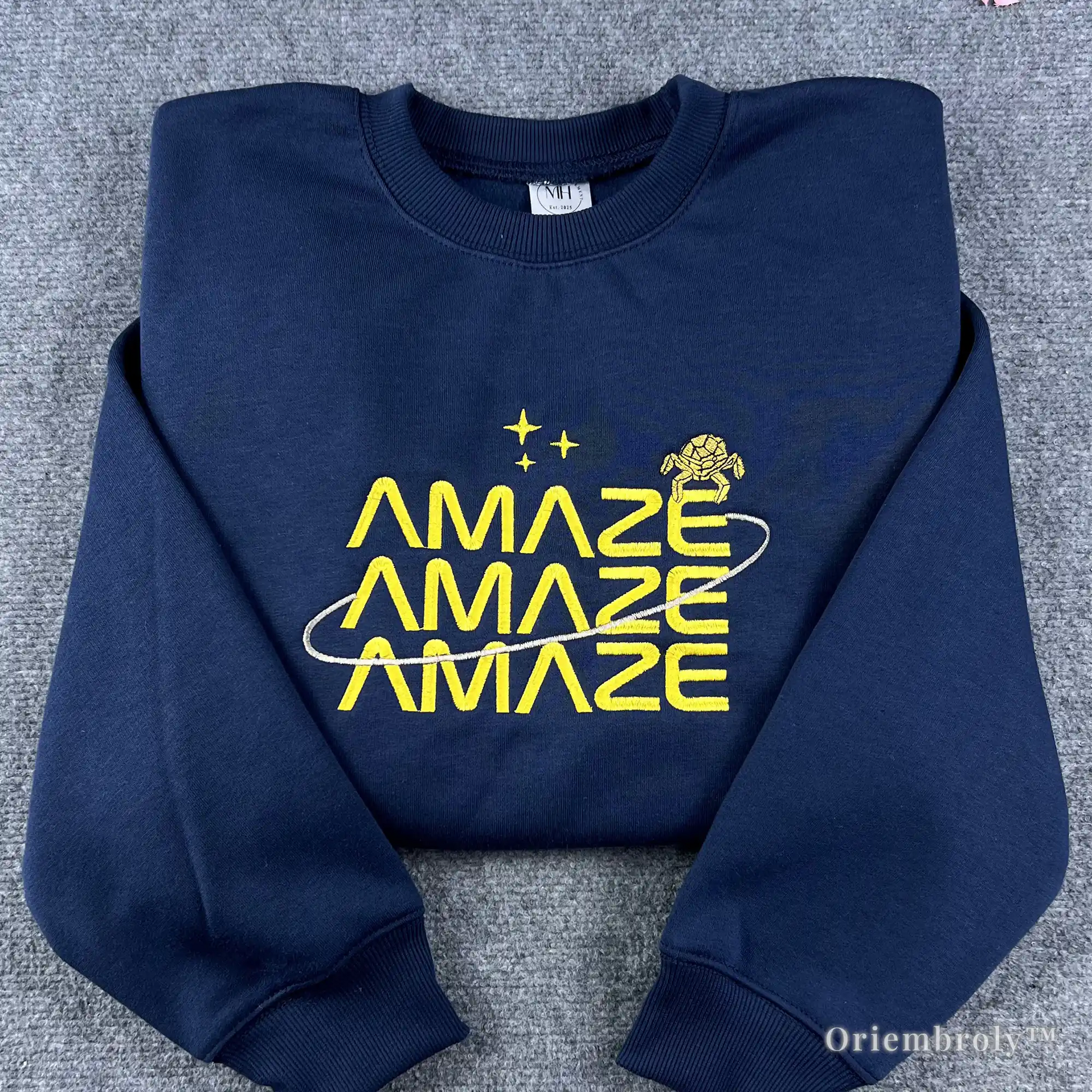 Premium navy blue crewneck sweatshirt with yellow "Amaze Amaze Amaze" embroidery. Inspired by Project Hail Mary book, featuring the alien Rocky and star motifs. Ideal for sci-fi fans