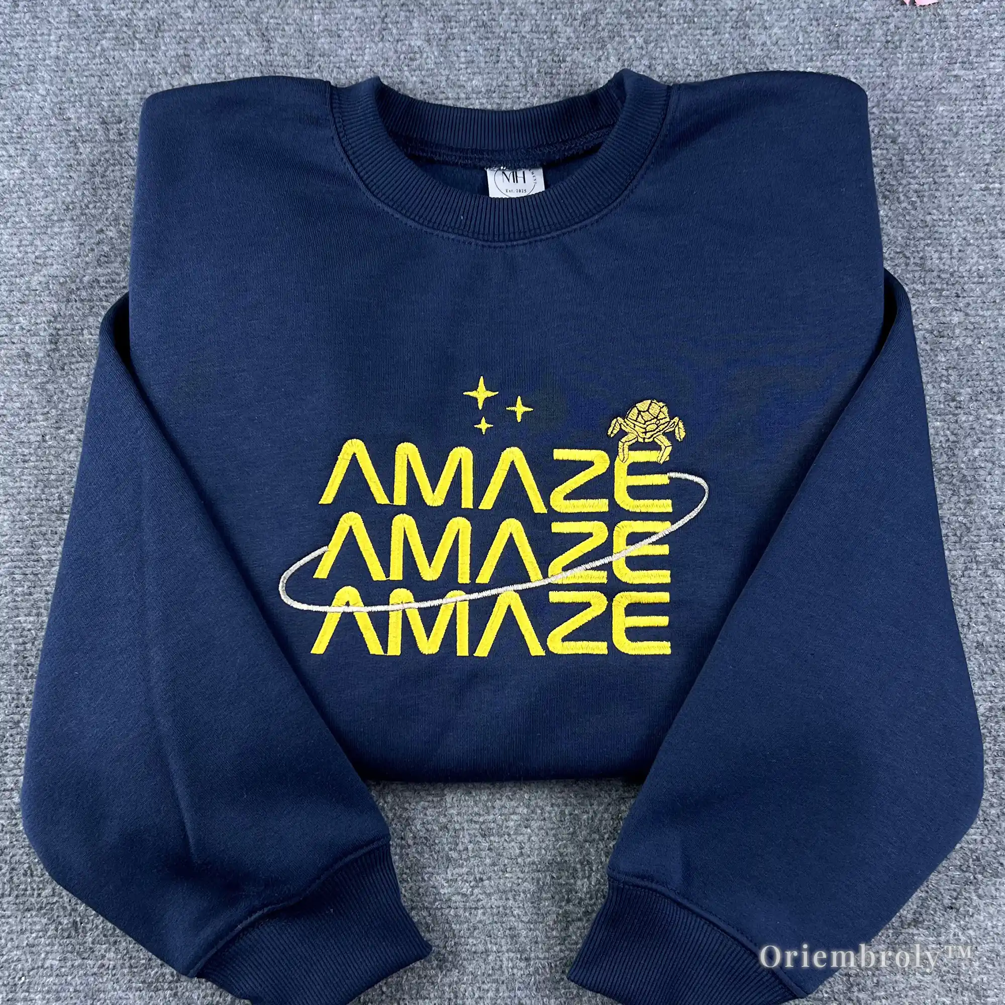 Premium navy blue crewneck sweatshirt with yellow "Amaze Amaze Amaze" embroidery. Inspired by Project Hail Mary book, featuring the alien Rocky and star motifs. Ideal for sci-fi fans