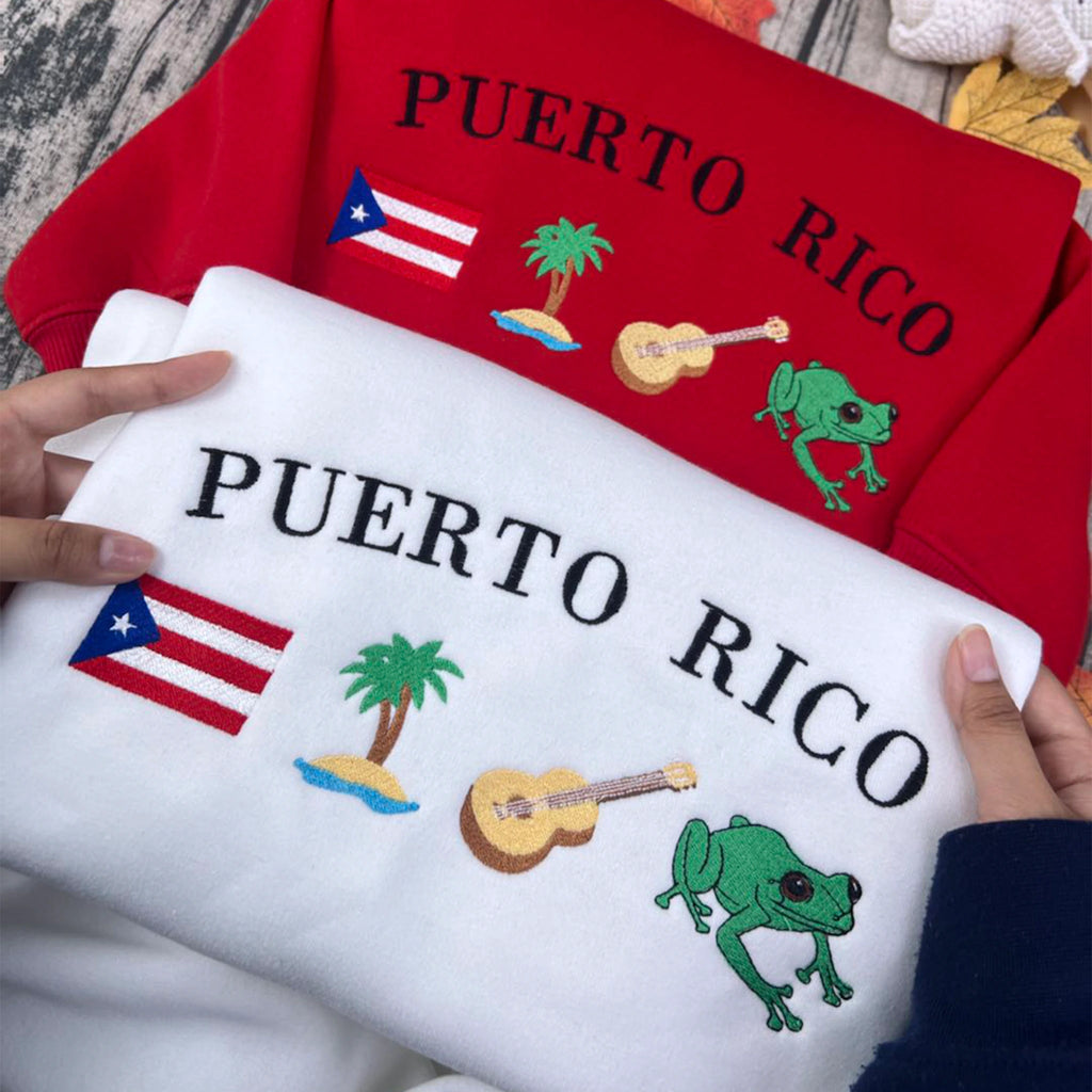 Puerto Rico embroidery sweatshirt featuring Boricua culture symbols like Taino designs, Coquí frog, guitar, palm tree, and island flag. Black cotton crewneck, soft and stylish.