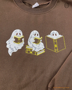 Overview of three cute ghosts reading books embroidered on a chocolate brown sweatshirt