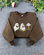 Flat lay of a chocolate brown crewneck sweatshirt embroidered with cute reading ghosts for bookish halloween outfit