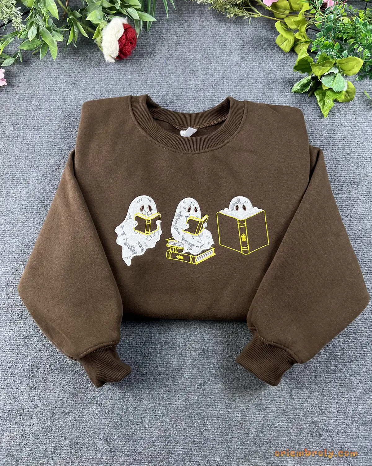Flat lay of a chocolate brown crewneck sweatshirt embroidered with cute reading ghosts for bookish halloween outfit