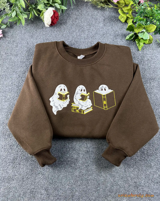 Flat lay of a chocolate brown crewneck sweatshirt embroidered with cute reading ghosts for bookish halloween outfit