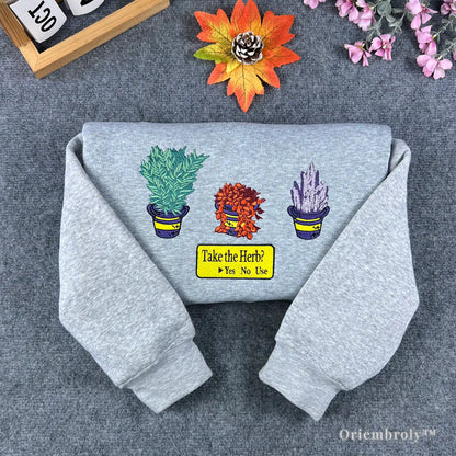 Grey Resident Evil sweatshirt featuring embroidered green, red, and blue healing herbs