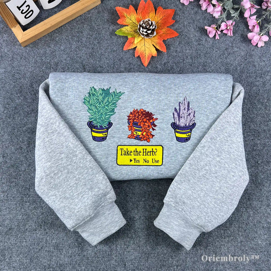 Grey Resident Evil sweatshirt featuring embroidered green, red, and blue healing herbs