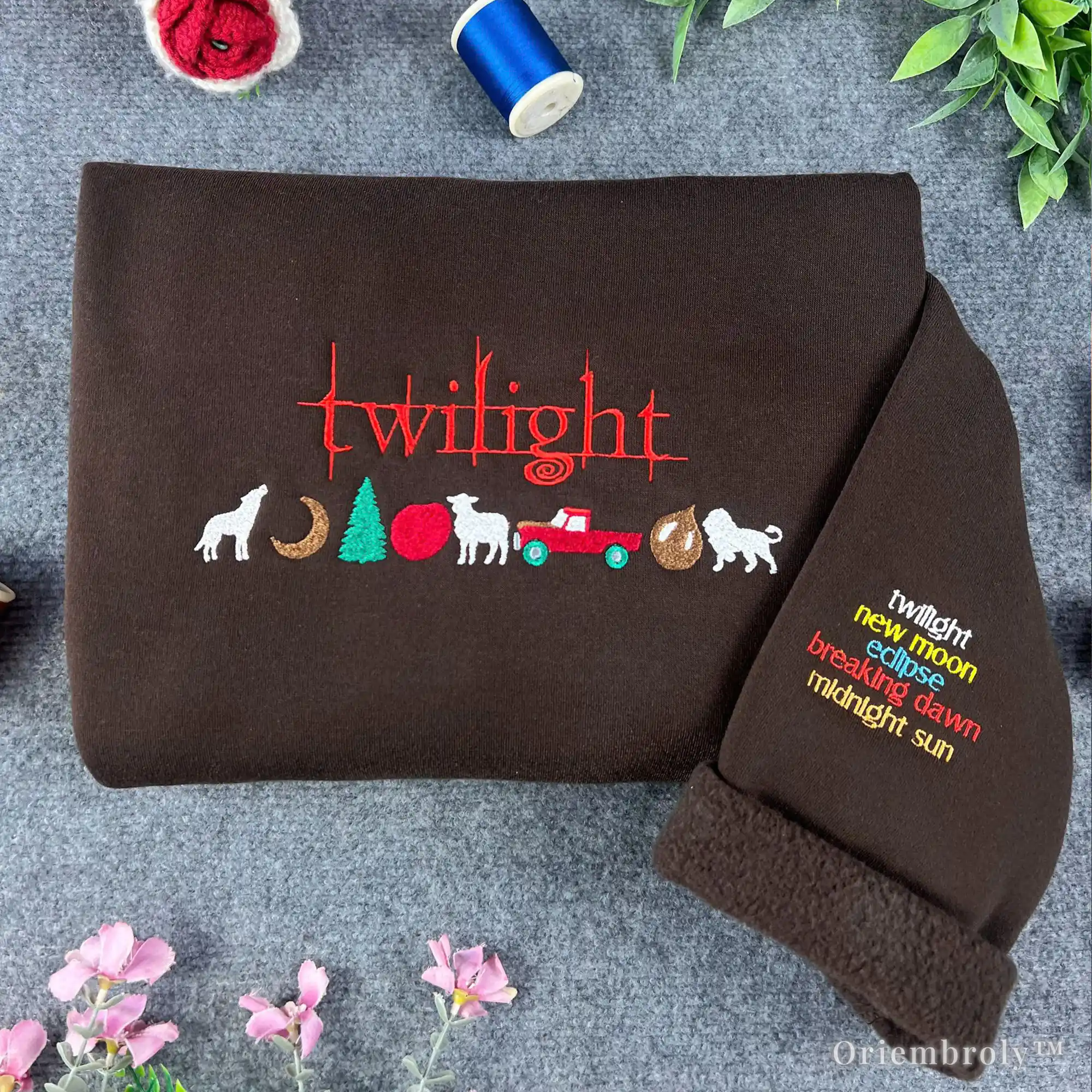 Brown blanket with embroidered 'twilight' series design on a textured surface with flowers and thread.