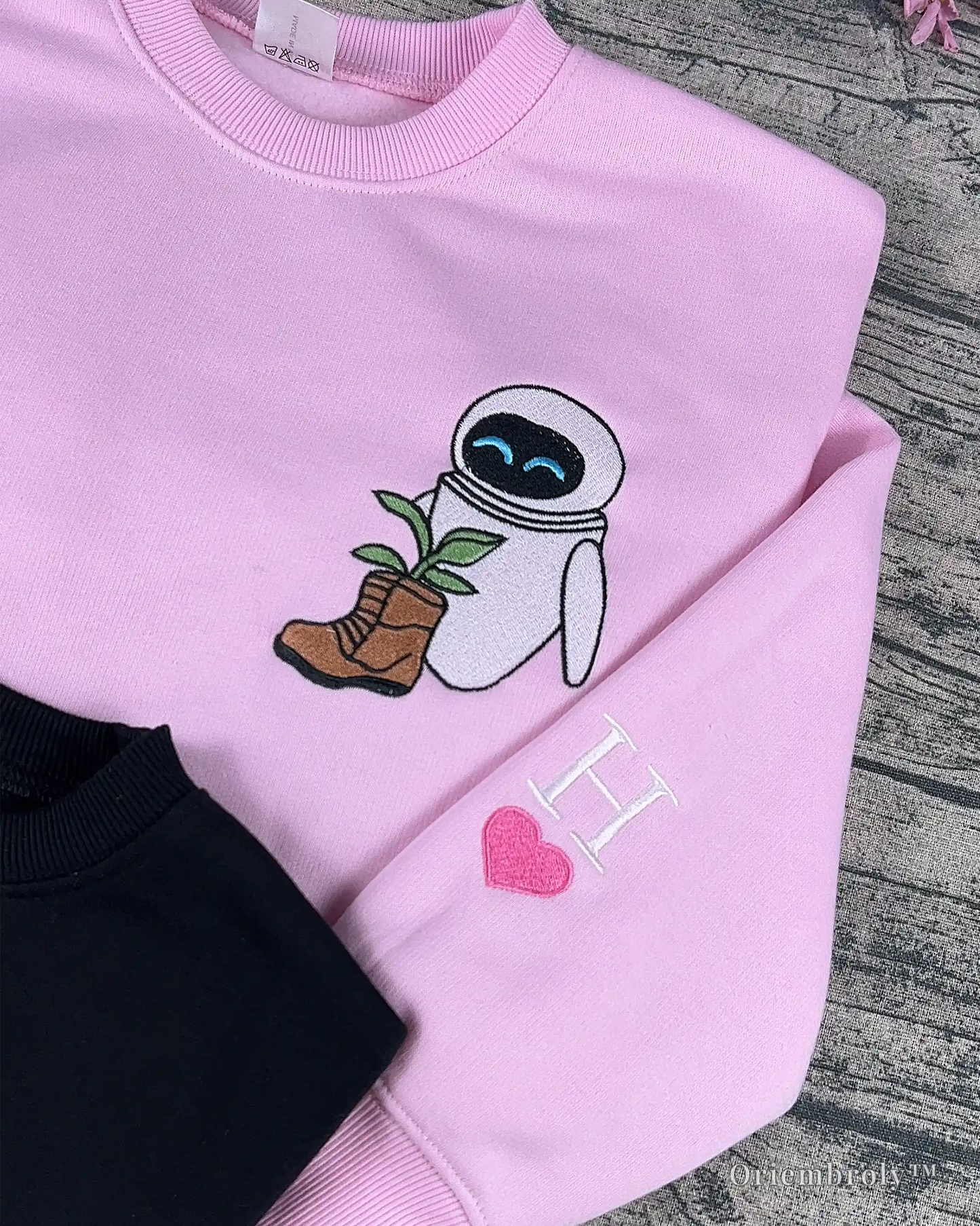 embroidered robot holding boot with plant on pink crewneck