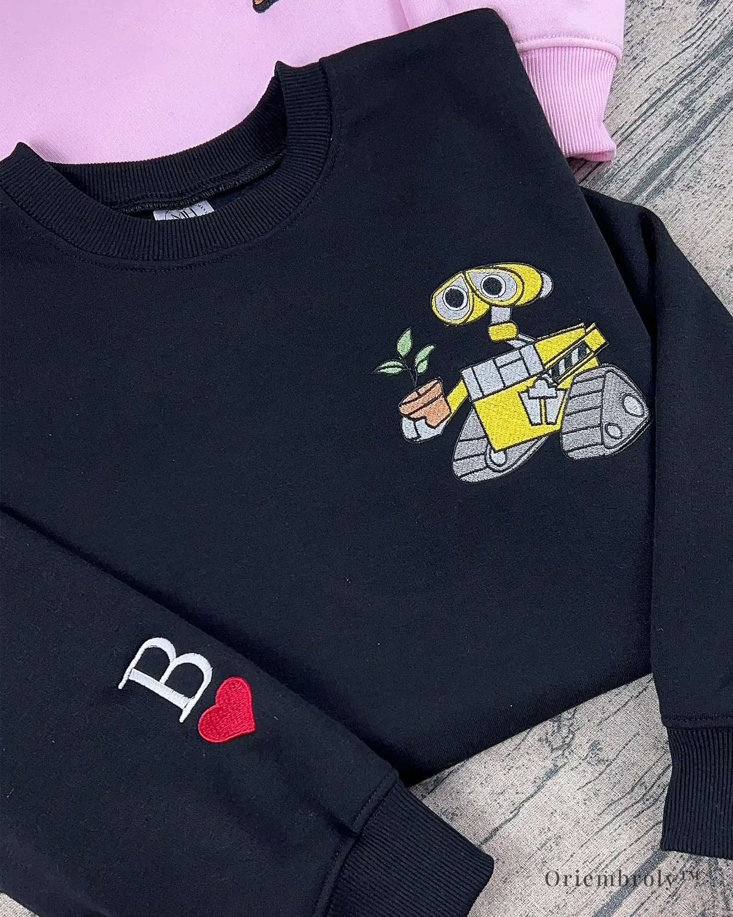 embroidered robot holding plant detail on black crewneck sweatshirt