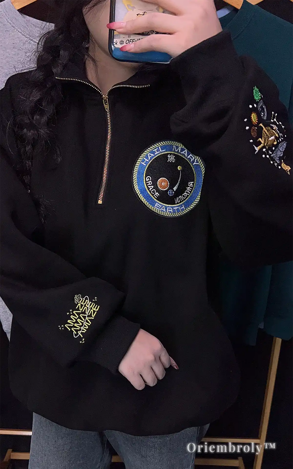 Black quarter-zip sweatshirt featuring a detailed embroidery collage of Rocky the Eridian, planets, and constellations. Exclusive fan merchandise for Project Hail Mary book club members