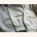 Three gray sweatpants with embroidered names on a neutral background