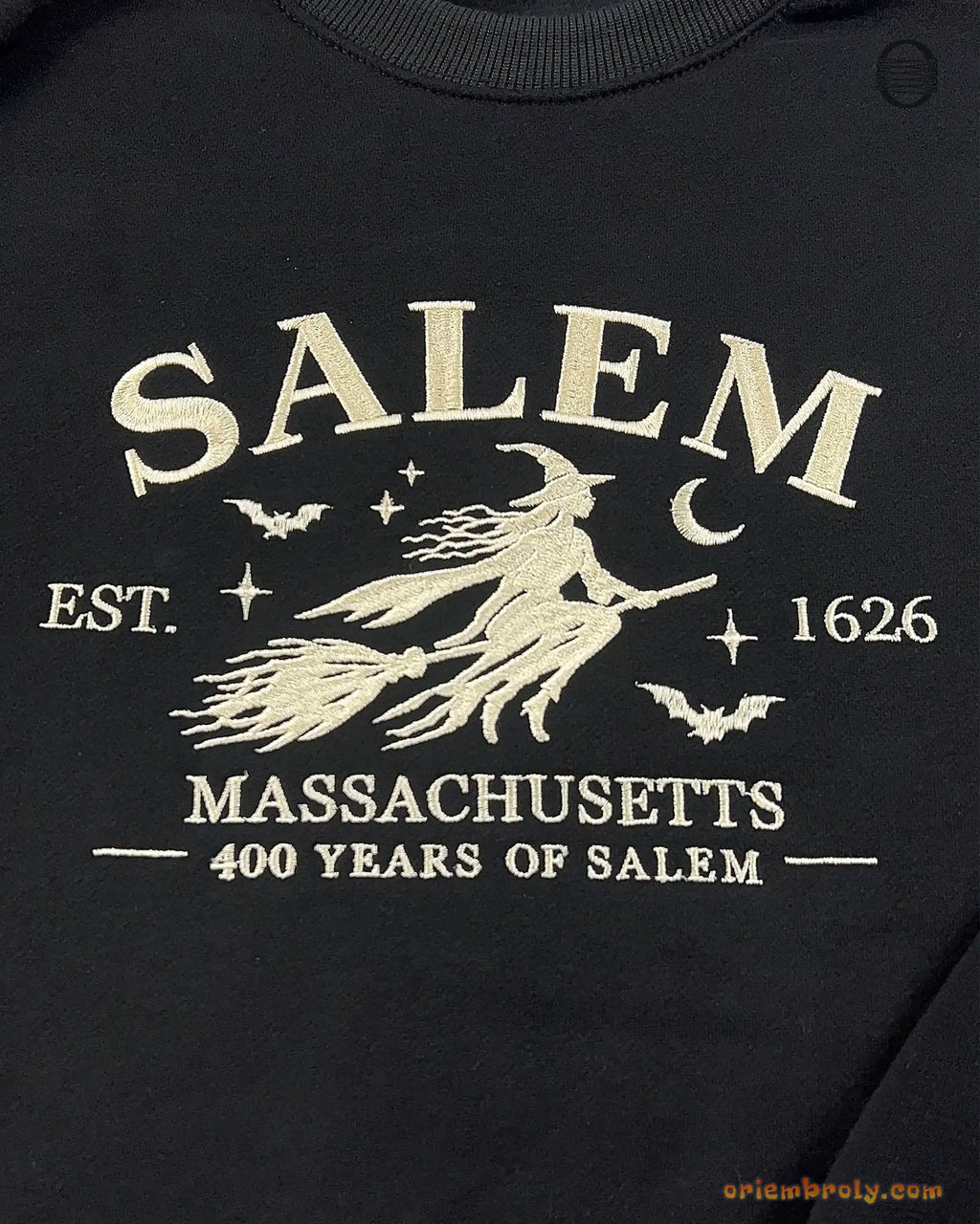 Close-up of vintage flying witch on a broomstick embroidery with Salem Massachusetts 400 Years of Salem text on a black sweater