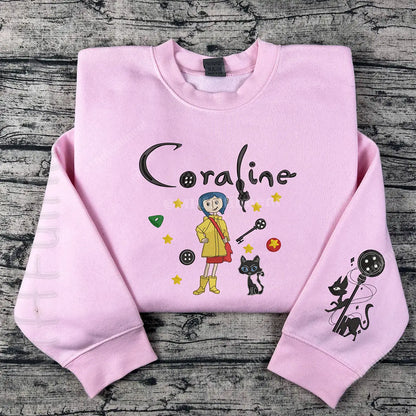 Pink sweatshirt with 'Coraline' design on a wooden surface