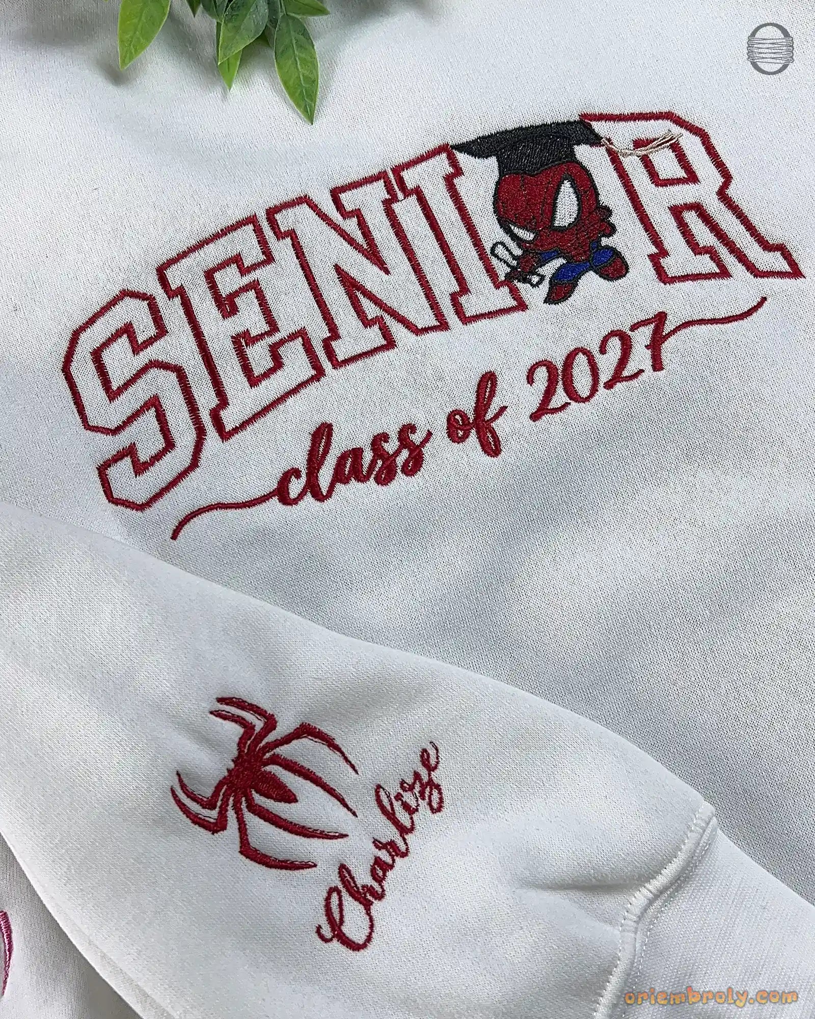 Close-up of red SENIOR Class of 2027 embroidery with Spider-Man icon and custom name on the sleeve cuff.