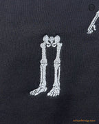 Detailed view of skeleton legs left behind embroidery on a black heavy blend hoodie