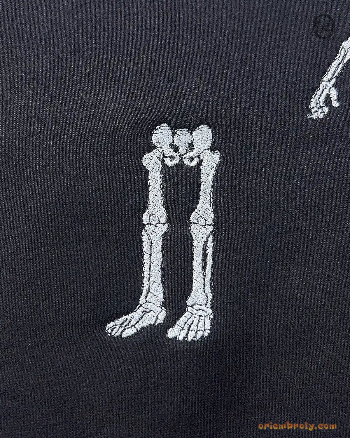 Detailed view of skeleton legs left behind embroidery on a black heavy blend hoodie