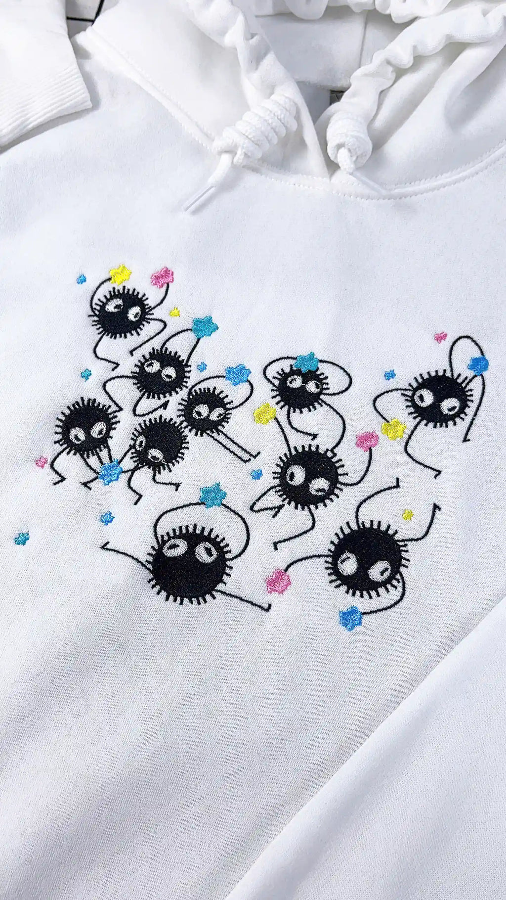 White hoodie with black embroidered designs on a white background