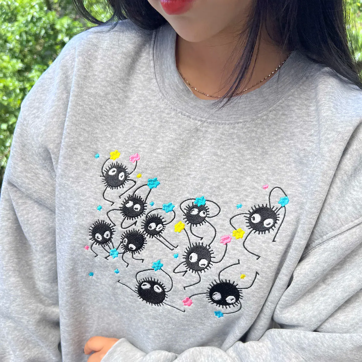 Person wearing a gray sweatshirt with cartoon character design outdoors