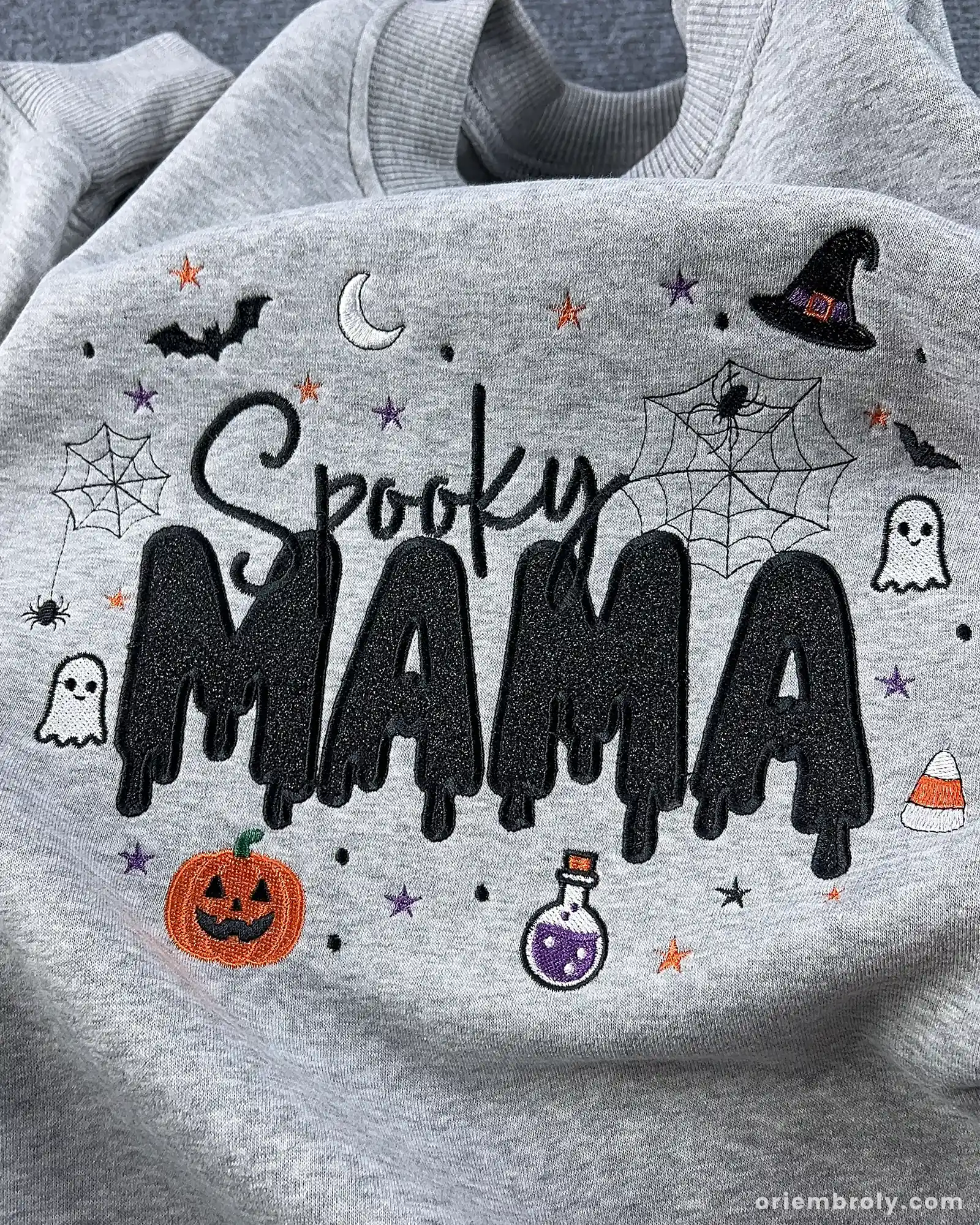 Detailed view of fine embroidery stitching on a light gray Spooky MAMA Halloween sweatshirt.