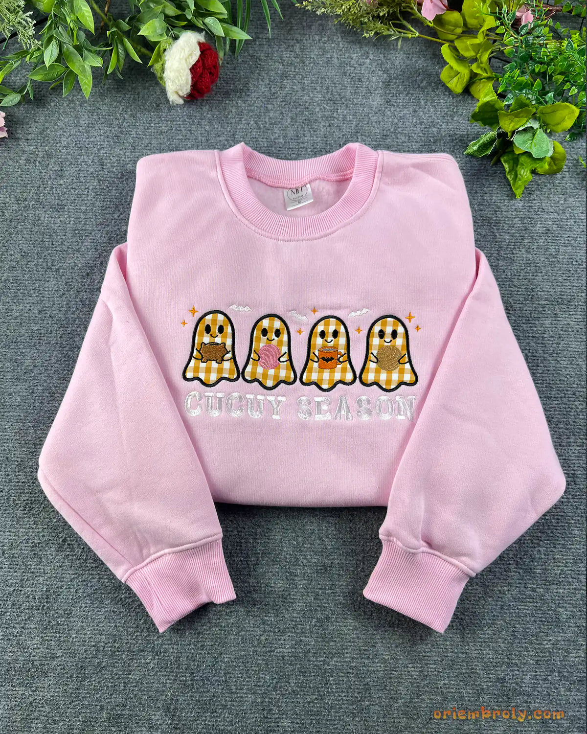 Flat lay of a light pink crewneck sweatshirt embroidered with Spooky Season text and four cute plaid pattern ghosts