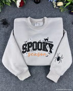 Flatlay view of sand beige spooky season halloween embroidered crewneck sweatshirt with sleeve spider detail.