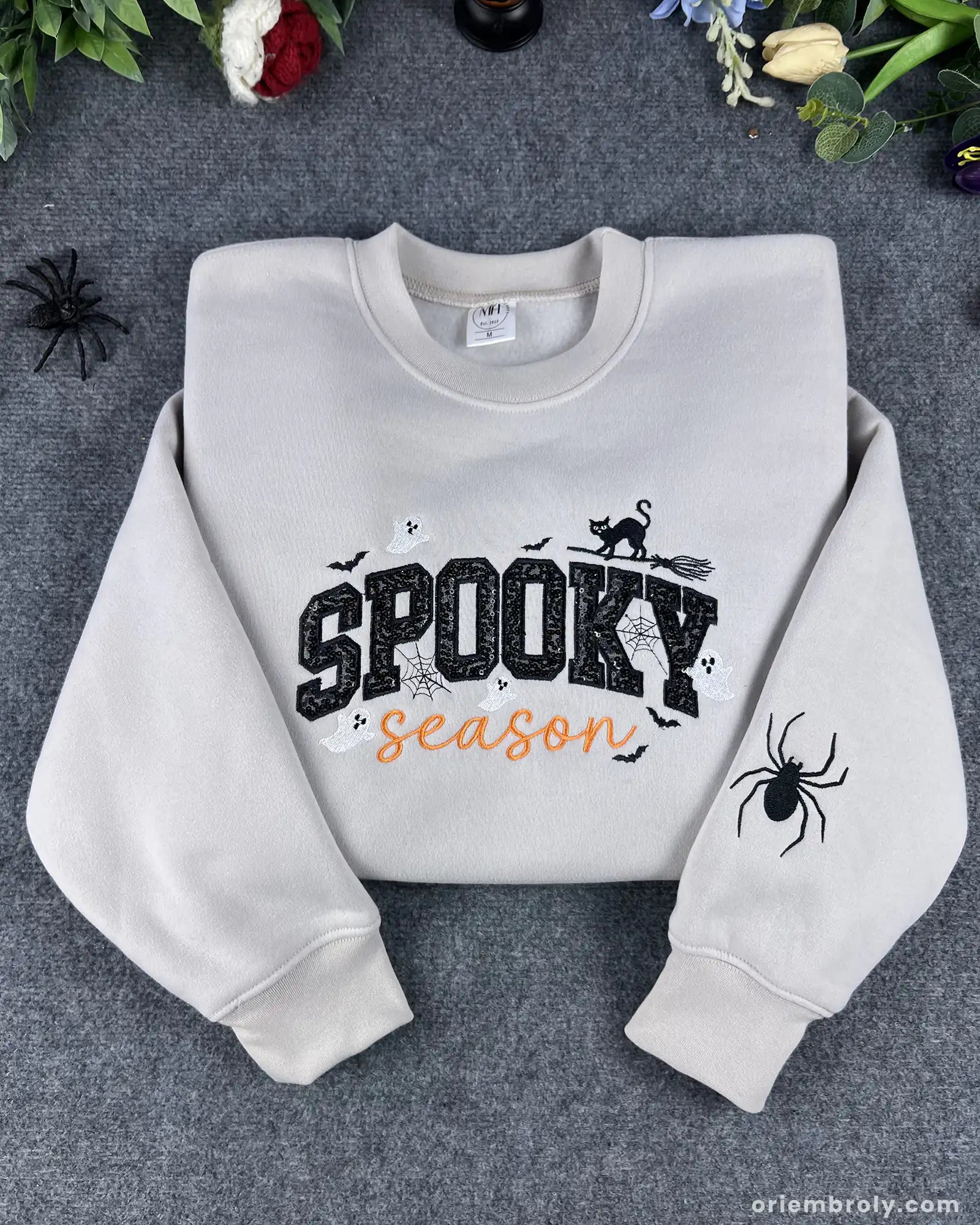 Flatlay view of sand beige spooky season halloween embroidered crewneck sweatshirt with sleeve spider detail.