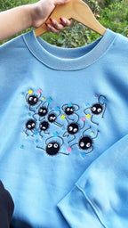 Blue sweatshirt with cartoon character design held by a hand on a blurred natural background