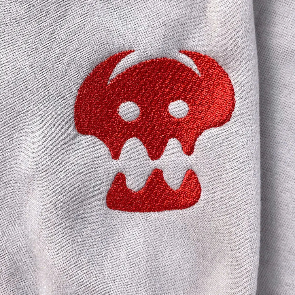 Red embroidered skull design on a gray sweatshirt