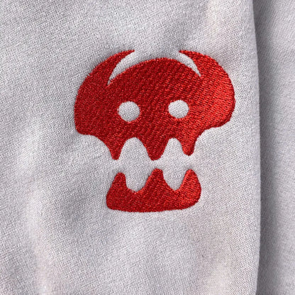 Red embroidered skull design on a gray sweatshirt