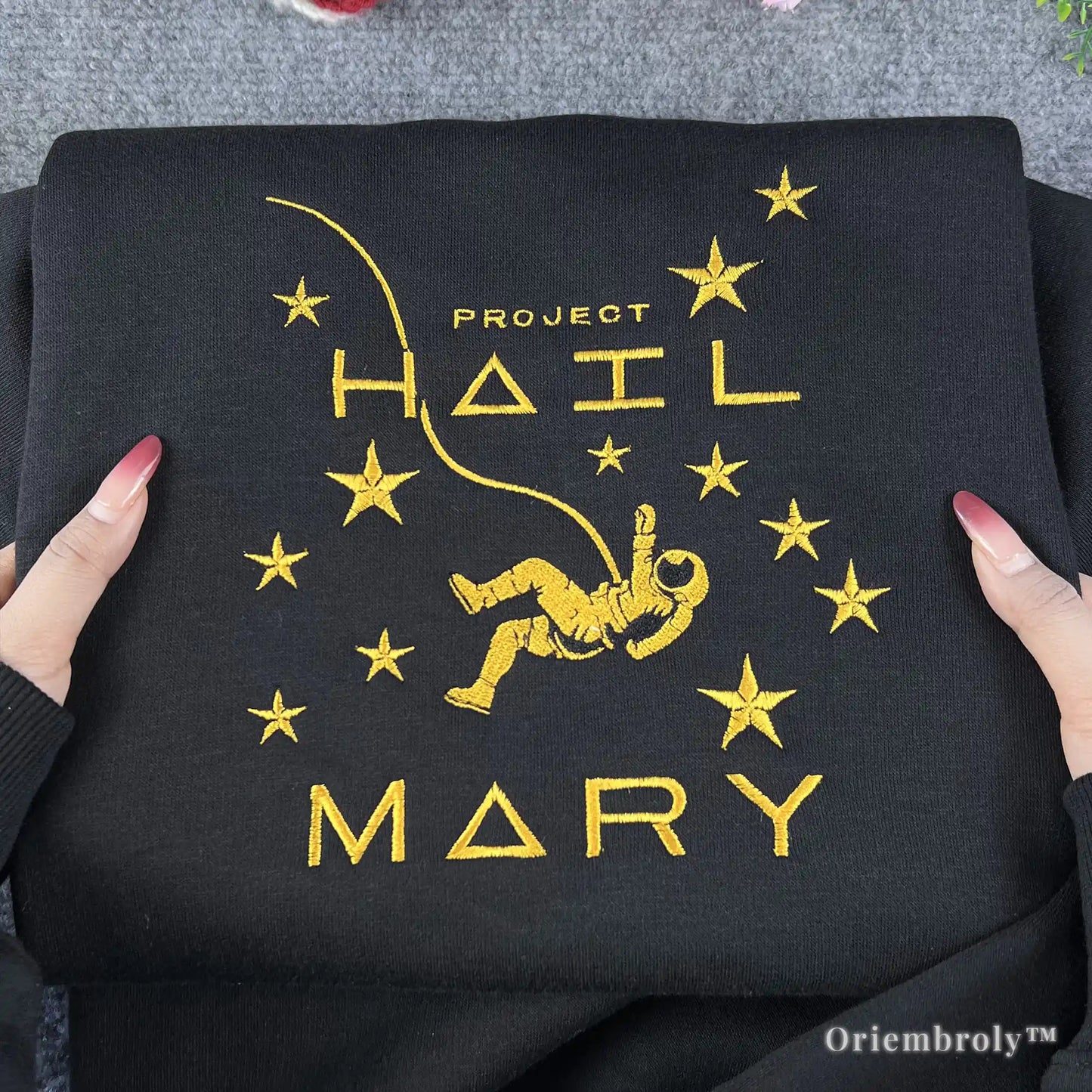 A unique and thoughtful gift for sci-fi readers and space enthusiasts: an embroidered Project Hail Mary sweatshirt. Features a minimalist cosmic design on cozy black fleece