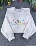 Flat lay of a white magical embroidered sweatshirt featuring Minnie mouse ears headband, princess crown, magic wand, and bow