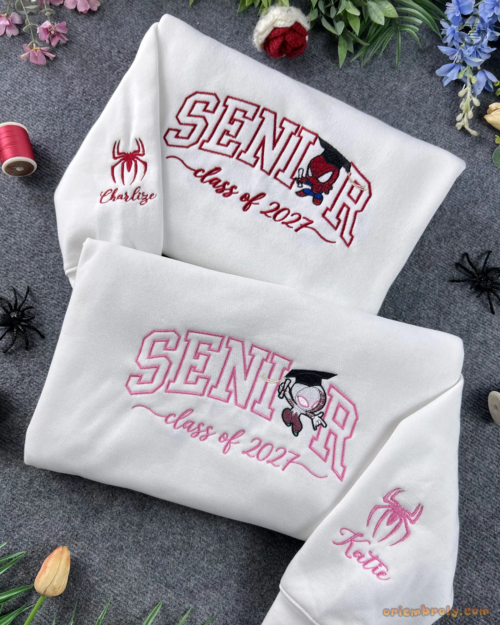Pair of white embroidered sweatshirts featuring SENIOR Class of 2027 text with Spider-Man graphics and custom sleeve cuffs.