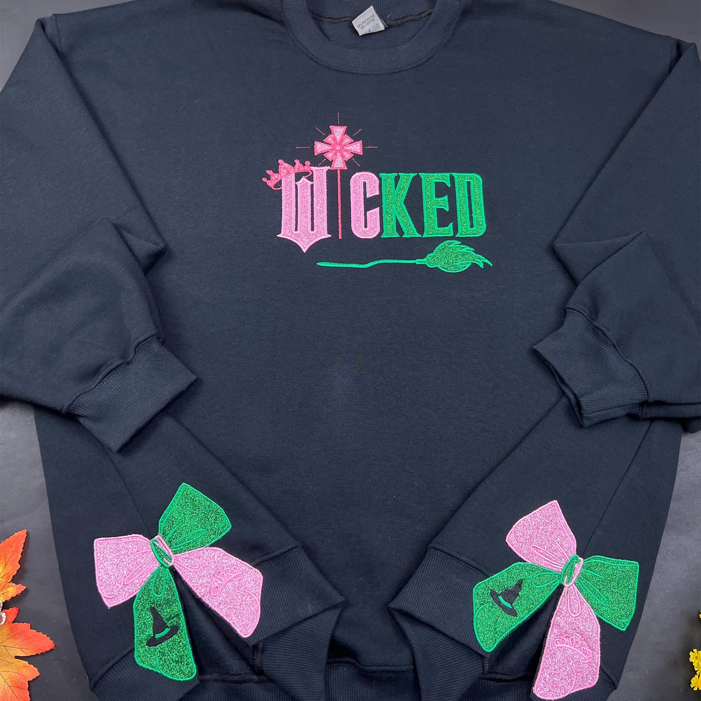 Wicked Movie embroidered sweatshirt featuring Defying Gravity design, side bow embroidery, and inspired by Glinda and Elphaba. Cozy and stylish for Broadway fans.