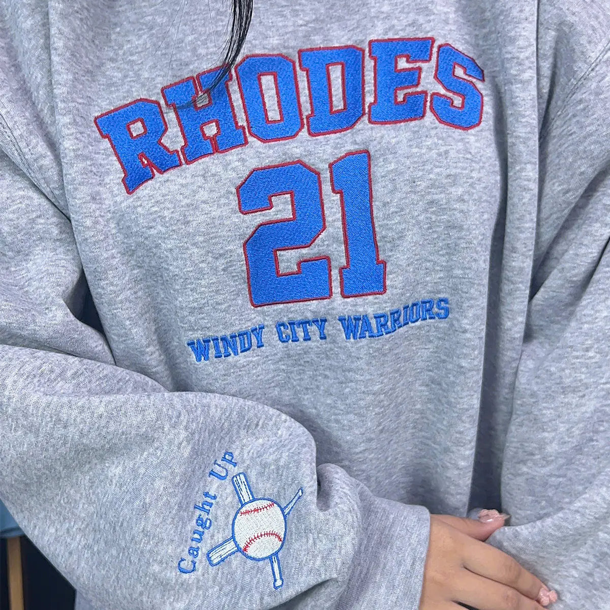 Gray sweatshirt with 'RHODES 21 Windy City Warriors' text and a logo on the sleeve.
