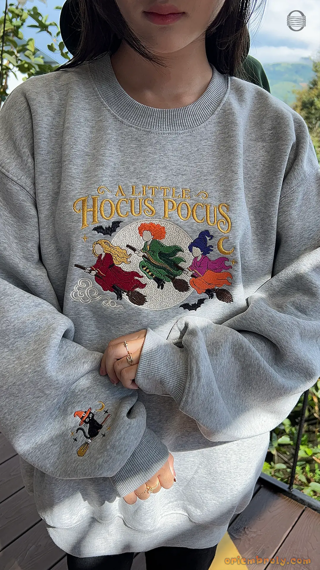 Model showcasing a gray A Little Hocus Pocus Halloween embroidered sweatshirt in an outdoor natural setting.