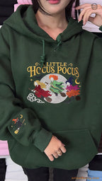 Model wearing an oversized forest green A Little Hocus Pocus embroidered hoodie indoors.