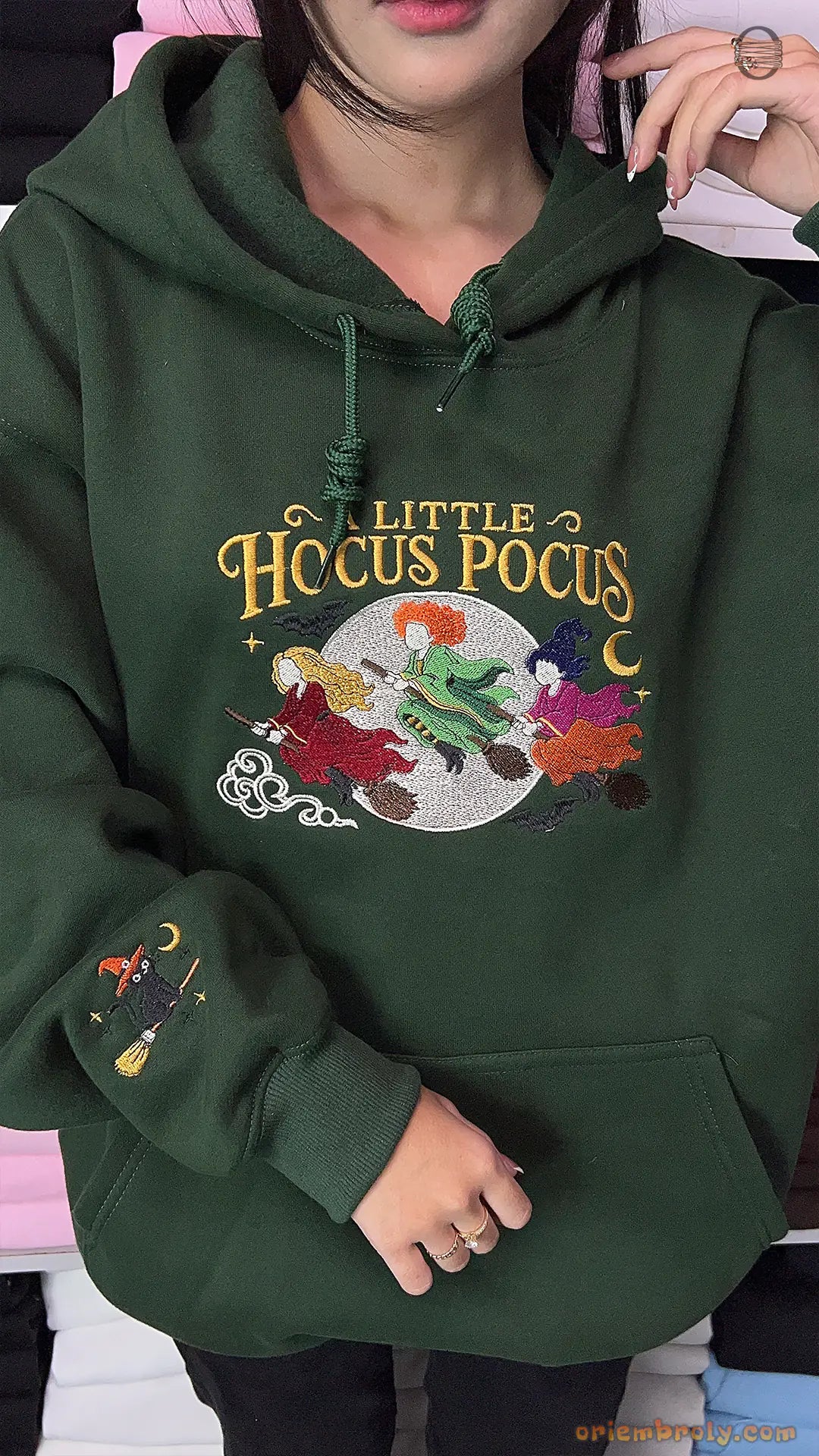 Model wearing an oversized forest green A Little Hocus Pocus embroidered hoodie indoors.