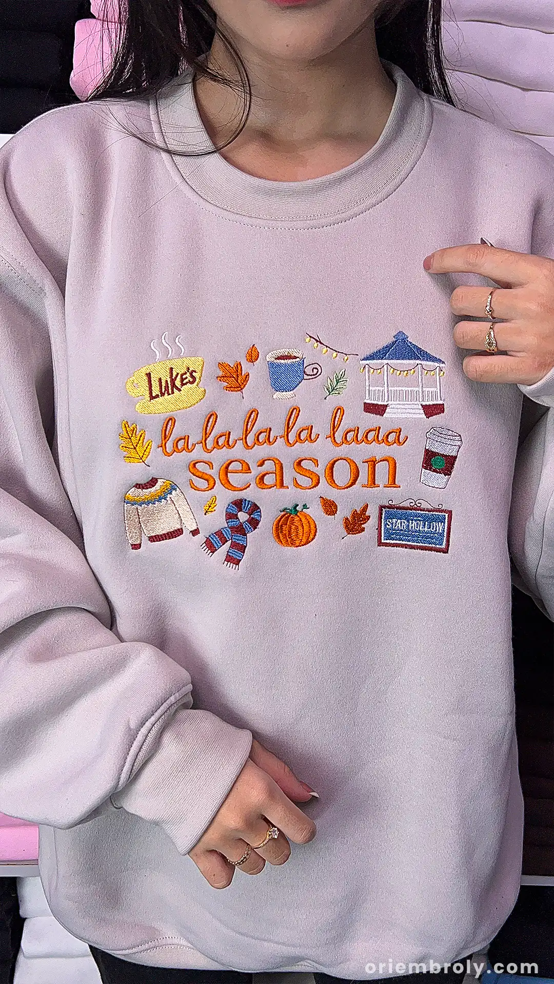 Model wearing an oversized beige La La La Season embroidered crewneck sweatshirt indoors.