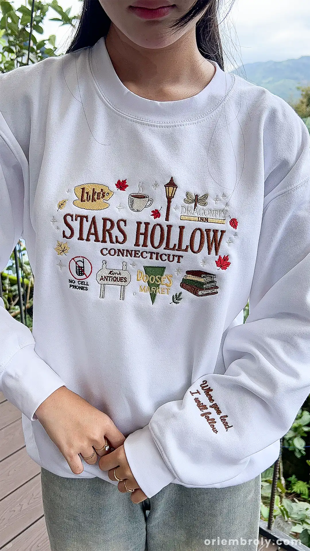 Model showcasing a white Stars Hollow Connecticut embroidered sweater in an outdoor setting.