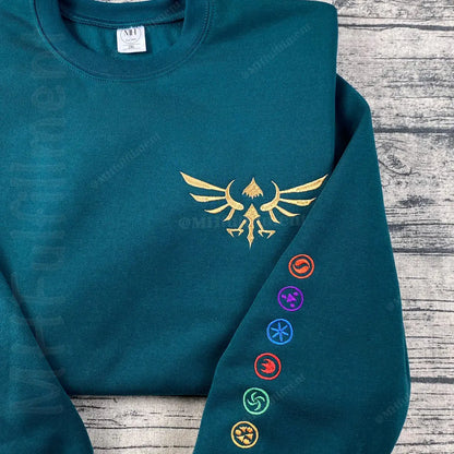 Teal hoodie with gold emblem and colorful symbols on a wooden surface